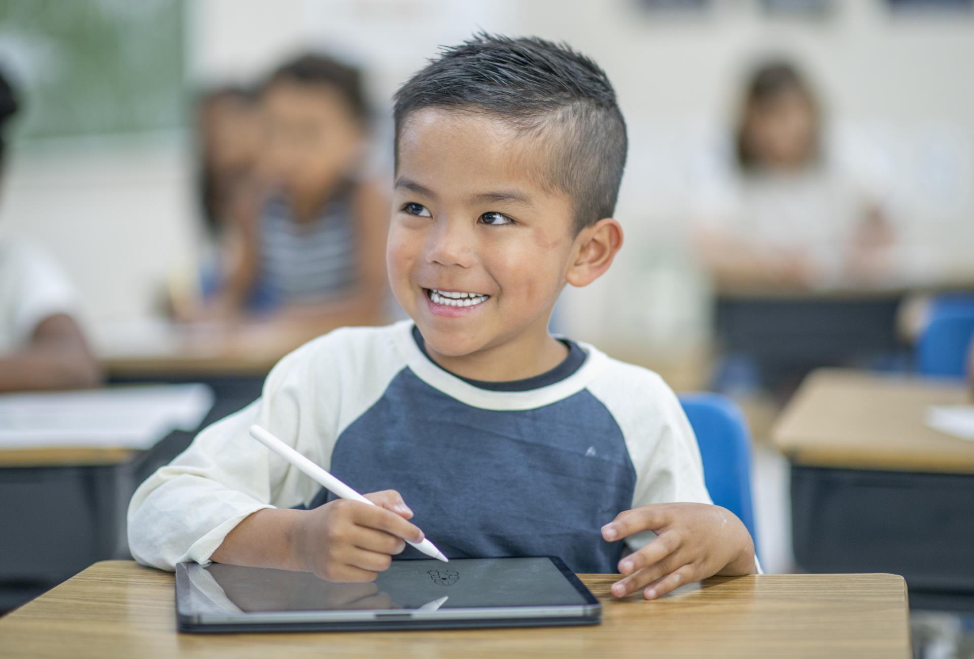 Smiling student using a tablet at their desk