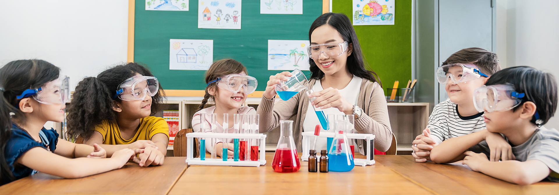 A picture of a teacher and students working on a science experiment together.