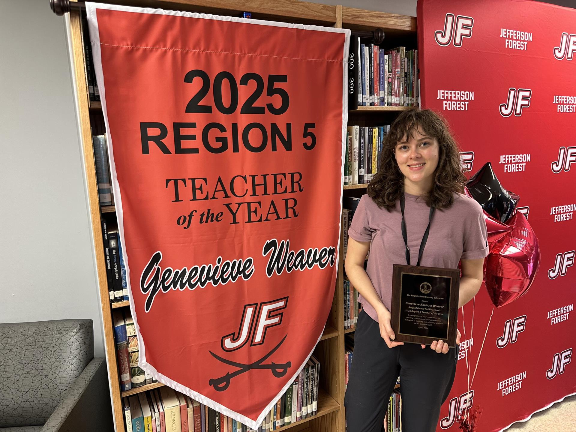 Genevieve Weaver smiling next to a 2025 Region 5 Teacher of the Year Banner