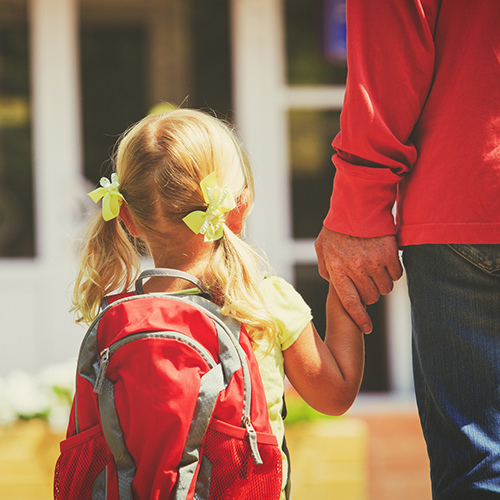Child wearing backpack holding and parent's hand